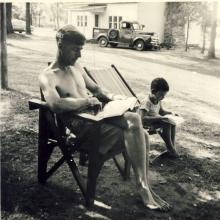 <p>1953, August - George Whalley with Chris, his son, reading at Kennebee Lake</p>